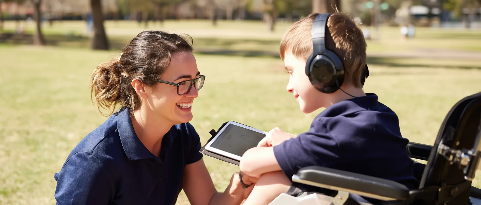 A practitioner meeting with a young person outdoors using a tablet.